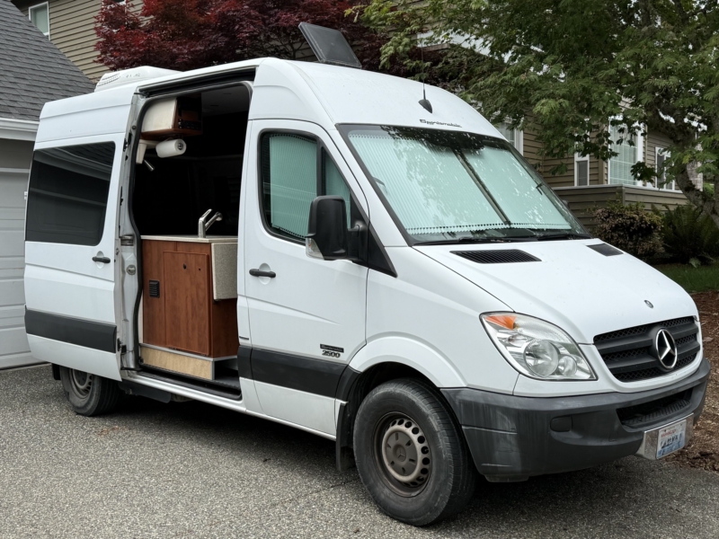 White Mercedes Sprinter camper van with the side door open