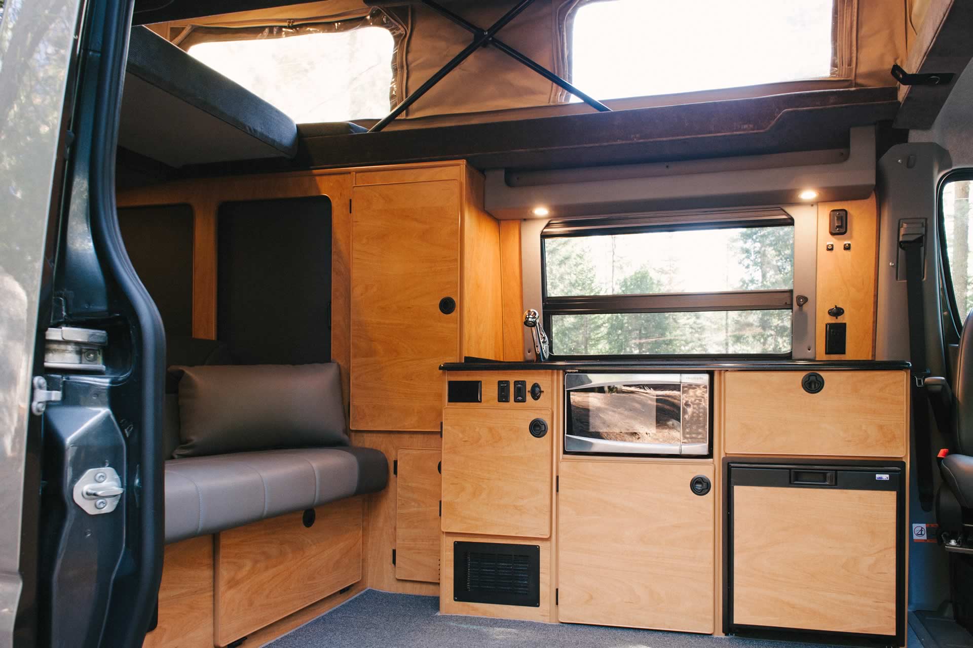 Interior view of Sportsmobile camper van converison with the penthouse top open.