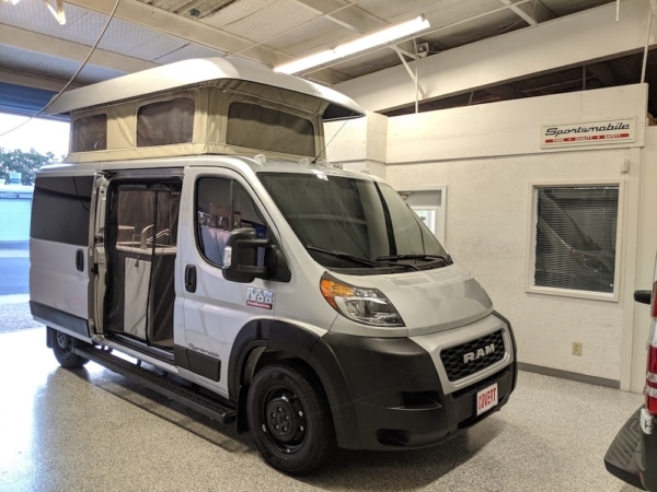 Light grey Dodge Promaster with popped up roof parked in the garage.