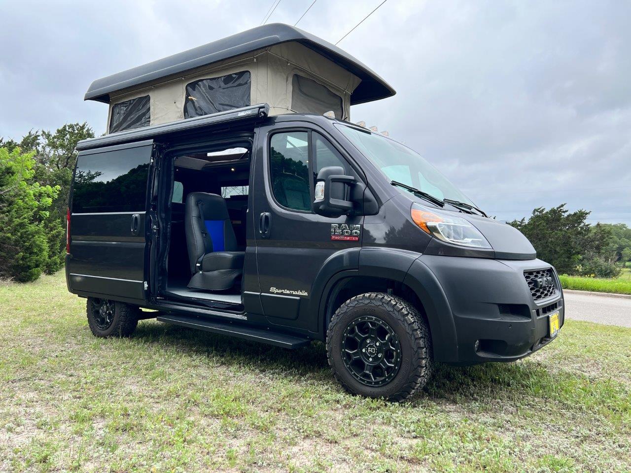 Black Dodge Promaster with popped up roof and opened door.