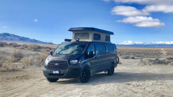Ford Transit with popped up roof parked in the desert.